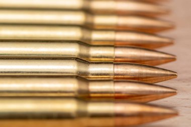 Kalaşnikof saldırı tüfeği için 7.62 kalibrelik mermili bir sıra. Arka planda, yakın plan, seçici odaklanma. Konsept: ödünç verilmiş silah satışı, silah ve mühimmat yardımı, silah tedariği.