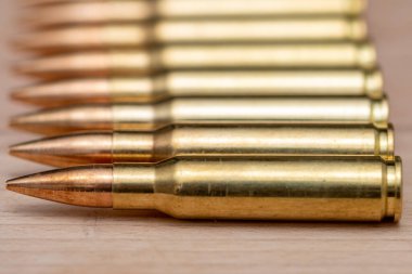 A row of cartridges with 7.62 caliber bullets for a Kalashnikov assault rifle on a textured background, close-up, selective focusing. Concept: sale of weapons under lend-lease, assistance with weapons and ammunition, arms supplies.