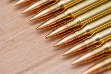 A row of cartridges with 7.62 caliber bullets for a Kalashnikov assault rifle on a textured background, close-up, selective focusing. Concept: sale of weapons under lend-lease, assistance with weapons and ammunition, arms supplies.