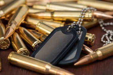 Ordu kimlik belgeleri dağınık sarı makineli tüfek fişeklerinin üzerinde duruyor, seçici odaklanma. Kavram: Askeri özel operasyon, Ukrayna 'da savaş, askere alma, askeri operasyonlar.