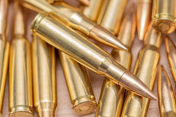 Kalaşnikof taarruz tüfeği için 7.62 kalibrelik mermilerin etrafa saçılması, yakın plan, seçici odaklanma. Konsept: ödünç verilmiş silah satışı, mühimmat yardımı, silah tedariği.