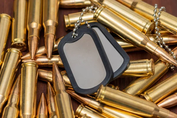 Ordu kimlik belgeleri dağınık sarı makineli tüfek fişeklerinin üzerinde duruyor, seçici odaklanma. Kavram: Askeri özel operasyon, Ukrayna 'da savaş, askere alma, askeri operasyonlar.