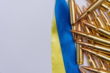Ukrayna bayrağı şeritleri, hafif arka planda bir Kalaşnikof saldırı tüfeği için 7.62 kalibrelik sarı fişekler, metin için alan, kavram: ödünç verilmiş silah tedariğinde yardım.
