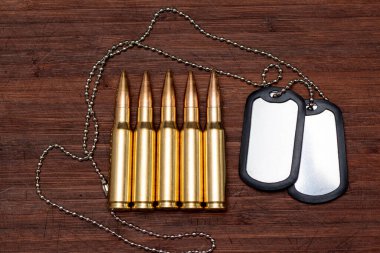 Canlı askeri kartuşlar ve ahşap bir arka planda ordu kimlik izleri. Kavram: Orduda suç, orduda hizmet, kavga, savaş suçu.