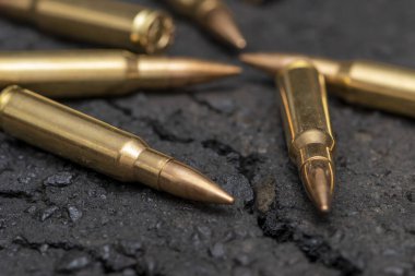 Kentteki asfaltta duran bir Kalaşnikof taarruz tüfeği için 7.62 kalibrelik mermilerin etrafa saçılması, yakın çekim, seçici odaklanma. Kavram: Ukrayna 'daki savaş, şehir çatışmaları, çatışmalar.