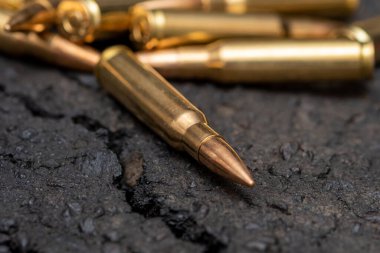 Kentteki asfaltta duran bir Kalaşnikof taarruz tüfeği için 7.62 kalibrelik mermilerin etrafa saçılması, yakın çekim, seçici odaklanma. Kavram: Ukrayna 'daki savaş, şehir çatışmaları, çatışmalar.