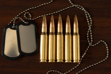 Canlı askeri kartuşlar ve ahşap bir arka planda ordu kimlik izleri. Kavram: Orduda suç, orduda hizmet, kavga, savaş suçu.