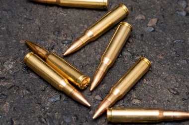 Kentteki asfaltta duran bir Kalaşnikof taarruz tüfeği için 7.62 kalibrelik mermilerin etrafa saçılması, yakın çekim, seçici odaklanma. Kavram: Ukrayna 'daki savaş, şehir çatışmaları, çatışmalar.