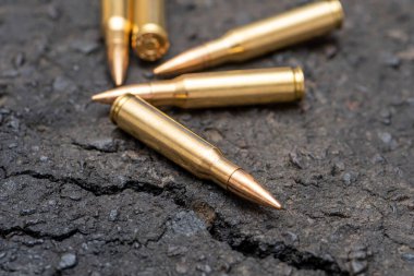 Kentteki asfaltta duran bir Kalaşnikof taarruz tüfeği için 7.62 kalibrelik mermilerin etrafa saçılması, yakın çekim, seçici odaklanma. Kavram: Ukrayna 'daki savaş, şehir çatışmaları, çatışmalar.