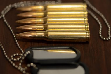 Canlı askeri kartuşlar ve ahşap bir arka planda ordu kimlik izleri. Kavram: Orduda suç, orduda hizmet, kavga, savaş suçu.