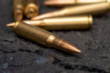 Kentteki asfaltta duran bir Kalaşnikof taarruz tüfeği için 7.62 kalibrelik mermilerin etrafa saçılması, yakın çekim, seçici odaklanma. Kavram: Ukrayna 'daki savaş, şehir çatışmaları, çatışmalar.