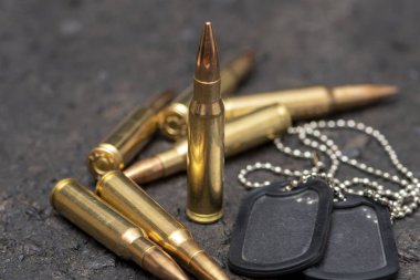 Çatlamış asfaltın dokulu arka planında canlı mühimmat ve ordu kimlik belgeleri var. Kavram: Orduda suç, askerlik, savaş.