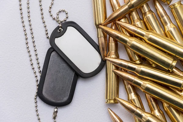 Ordu kimlik kartları, dağınık makineli tüfek fişekleri ve beyaz bir arka planda gerçek mühimmat, seçici bir odak. Kavram: Askeri özel operasyon, askere alma, askeri harekat.