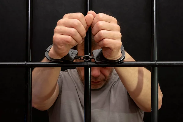 バーの後ろの独房に手錠をかけられた男 裁判所の囚人 有罪判決を受けた人への裁判所の判決 刑務所の用語 — ストック写真