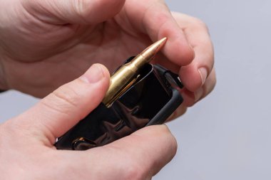 Erkek bir avcı hafif arka planda bir tüfek şarjörü için şarjör doldurur, bir savaş silahı hazırlar..