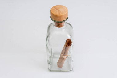 Cam bir şişeye sarılmış eski bir kağıt not ve arka planda bir mantar var. Konsept: deniz postaları, adadan gelen bir mesaj, yardım talebi, gemi enkazı, el yazması ya da parşömen..