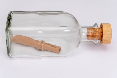 Cam bir şişeye sarılmış eski bir kağıt not ve arka planda bir mantar var. Konsept: deniz postaları, adadan gelen bir mesaj, yardım talebi, gemi enkazı, el yazması ya da parşömen..
