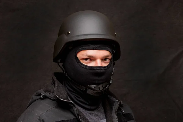 Portrait of a military soldier in a bulletproof vest and balaclava, army helmet on his head, black background. Concept: volunteer at war, war in Ukraine, civil self-defense, army unit.