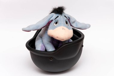 Oyuncak bir eşek askeri kaskın içinde, beyaz bir arka planda, izole bir şekilde oturuyor. Kavram: Ukrayna 'daki savaş, savaştaki çocuk oyuncakları.