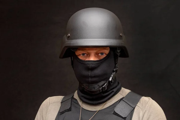 muscular military 45-50 years old in a bulletproof vest and balaclava, army helmet on his head, black background. Concept: volunteer at war, war in Ukraine, civil self-defense, army unit.