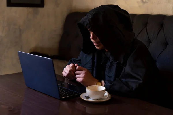 一个穿着黑色帽衫的年事已高的僧人的肖像 50岁 在笔记本电脑上工作 坐在桌子旁 声音暗淡 — 图库照片