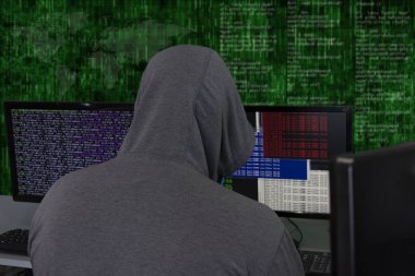 Bir bilgisayar korsanı soyut bir arkaplanda bilgisayar monitörlerinin arkasında oturuyor ve sunuculara virüs ile saldırıp hackliyor. Yanlış bilgilendirmenin yaratılması ve yayılması, DDOS saldırısı.