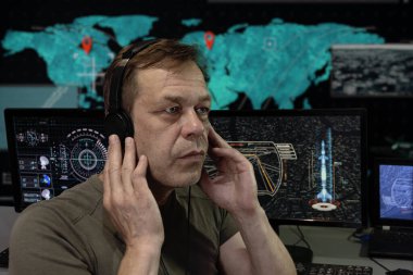 Bir askeri uzmanın duygusal portresi kulaklıklar, bilgisayar monitörleri. Konsept: Roket fırlatma, insan gözlemi, analitik merkez.