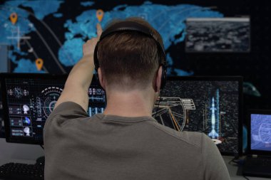 Kulaklık takan gizli bir ajan askeri istihbarat merkezinde monitörleri ve monitörleri izliyor. Kavram: İnsan gözetimi, hükümet görevlisi, askeri istihbarat subayı.