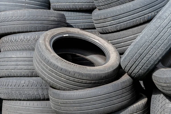 Old car tires, worn-out car tire tread, a dump of used tires from used cars. Environmental pollution.