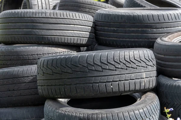 Old car tires, a pile of old car tires, a dump of worn-out tires from used cars. Environmental pollution. Throw away the tires,