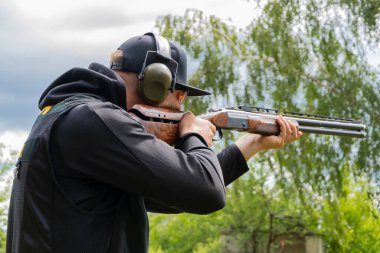 A male shooter aims a sporting double-barreled hunting rifle, target shooting, selective focus.