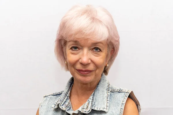 Portrait of a beautiful elderly woman 60-65 years old on a light background.