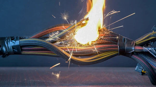 Electrical wiring and wires are lit on a dark background. A short circuit in the twisted wires from the computer. Flames, sparks and smoke.