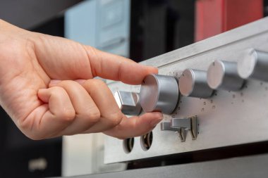 The volume knob on the amplifier turns the female hand, close-up, selective focus.