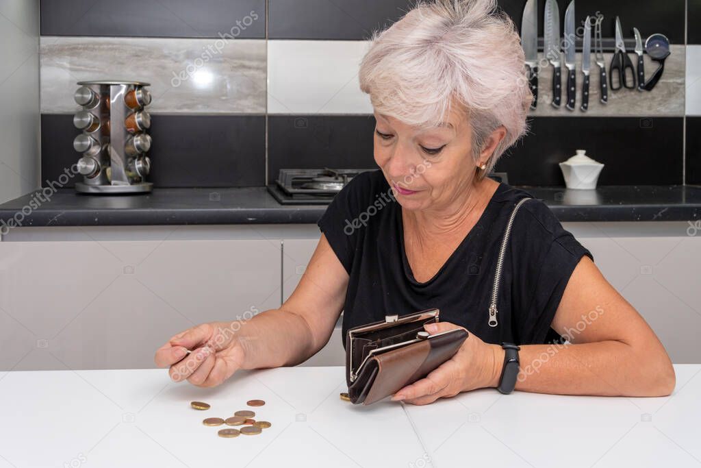 An elderly woman counts Small coins on the table, close-up. Concept: poverty and lack of livelihood, price increase.