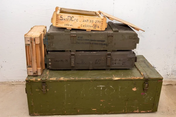 An open box with cartridges stands on a green box with weapons, open zinc containers. The text in Russian is the type of ammunition, caliber, type of projectile, quantity and weight.