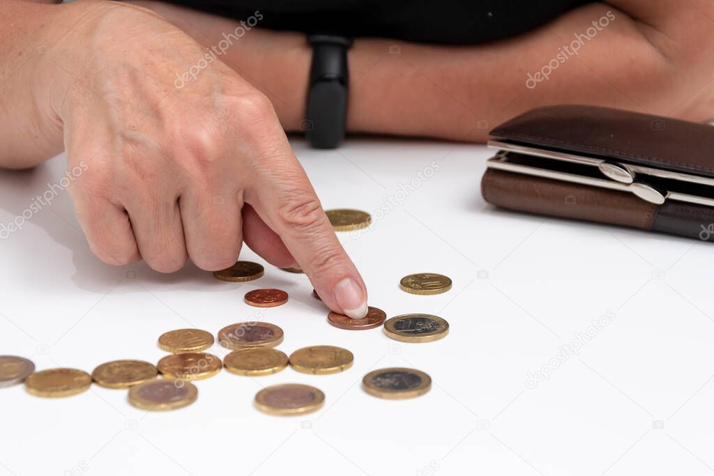 A woman`s hand puts a coin in her wallet. Concept: small pension, poverty, lack of money for living, euro cents