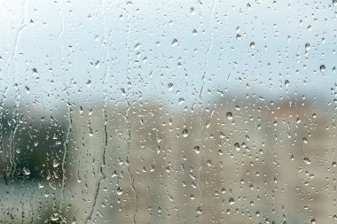 raindrops on window glass, blurred cityscape