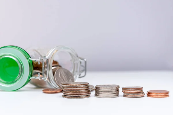 In a glass jar, metal coins, scattered change, a calculator for counting money on a white background, close-up, selective focus.Concept: financial savings, expenses and income.