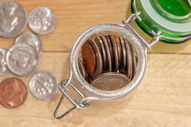 An open jar with small coins of American cents, scattered money on a wooden table top view, close-up, selective focus. A concept for business and finance, savings and price increases.