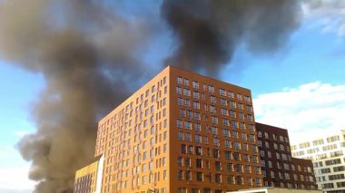 A fire in a multi-storey building, the building is burning, black smoke rises up. Concept: fire safety in case of natural disasters. fire in the building.