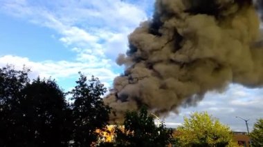 There is a fire in the building, the roof and upper floors are burning, black smoke rises up. Concept: fire safety in case of natural disasters, hit by a projectile or a bomb.