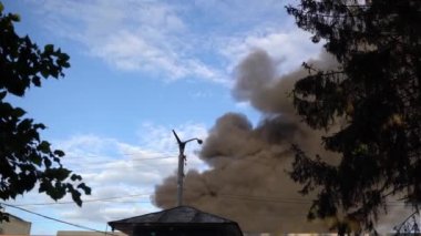 There is a fire in the building, the roof and upper floors are burning, black smoke rises up. Concept: fire safety in case of natural disasters, hit by a projectile or a bomb.