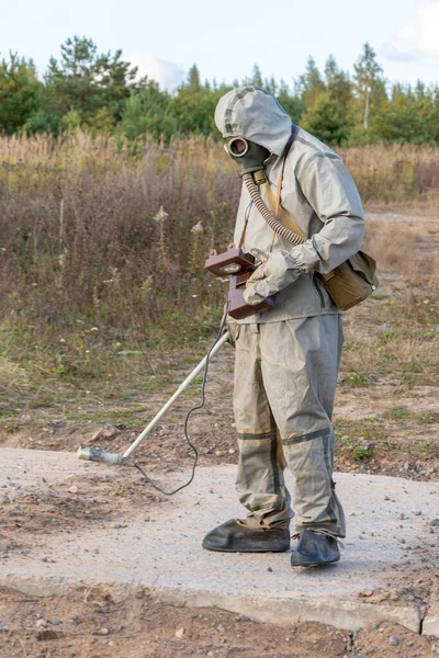 一名戴化学防护罩和防毒面具的军人用自然剂量计测量辐射水平 即火灾产生的烟雾 辐射泄漏 辐射危险 — 图库照片