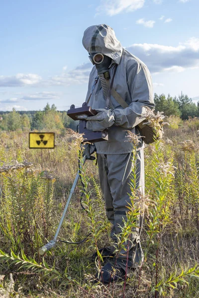 一个戴化学防护罩和防毒面具的军人用剂量计测量辐射水平 一个辐射危险信号 一个概念 辐射泄漏 感染的威胁 — 图库照片