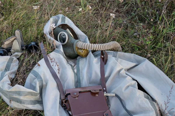 一个军用化学防护服 一个防毒面具 一个旧军队的绳索电话躺在受感染的草地上 — 图库照片