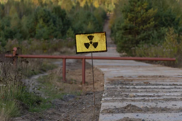 A sign of radioactive danger against the background of a forest yellowed by radiation. Concept: radioactive hazard, impact on nature, radiation dose.