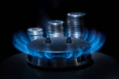 Gaz ocağı mavi bir alev ve seçici bir odak noktası olan bozuk paralarla yanar. Kavram: Ukrayna 'da doğalgaz ısınması, doğalgaz fiyatlarının yükseltilmesi.