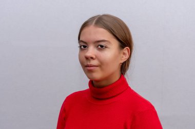 Açık arkaplanda uzun saçlı güzel bir genç kızın stüdyo portresi. Belki bir öğrenci ya da lise öğrencisidir..