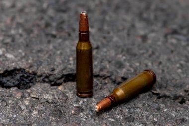 Çatlamış asfalt, seçici odaklanma ve ev yapımı geniş mermilerle yerlerinden edilmiş ağırlık merkezli mermiler. Kavram: ağır hasar, yasak mühimmat, savaş.